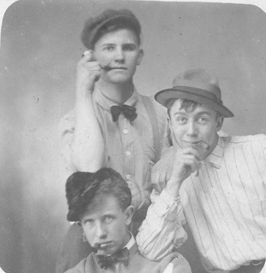 Historic photo showing three young men doing goofy poses 1920s.